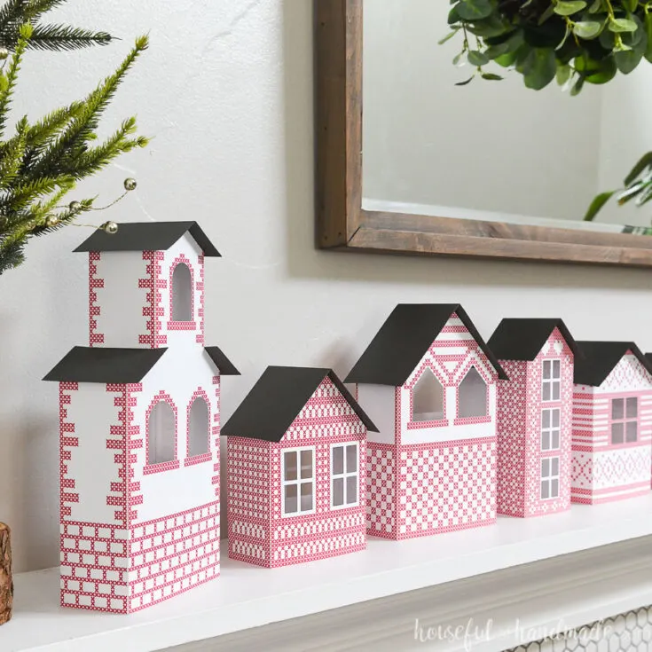 Closeup view of 5 paper houses making a Christmas village above the fireplace.