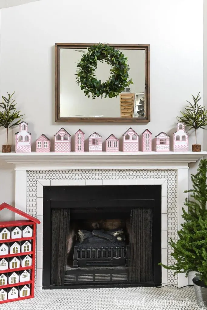 scandanavian christmas village paper houses on mantel with mirror and wreath