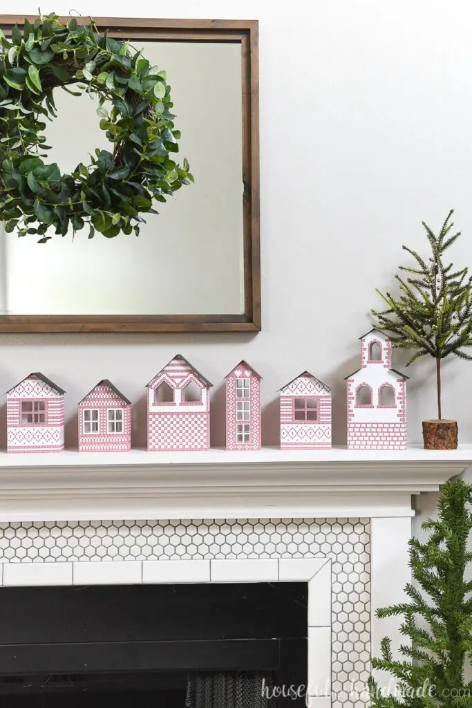 paper Christmas village on mantel with wreath above on mirror