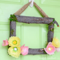 Square wreath made out of branches and tissue paper flowers to make a spring wreath.