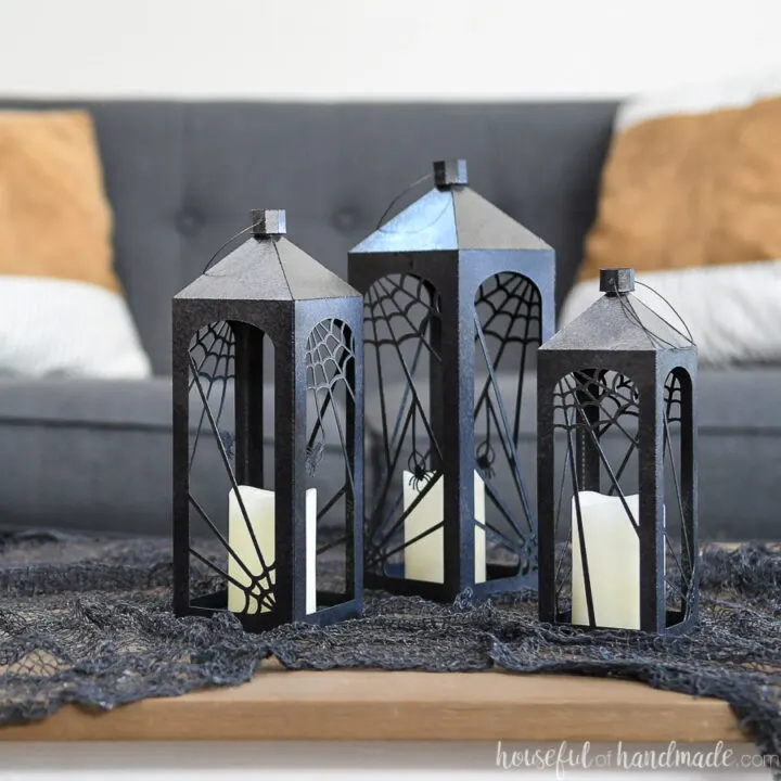 Three paper Halloween lanterns on a table with black creepy cloth.