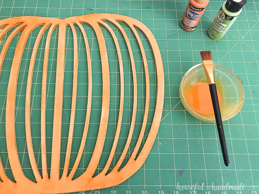 Plywood pumpkin shape painted with a watered down orange paint mixture. 