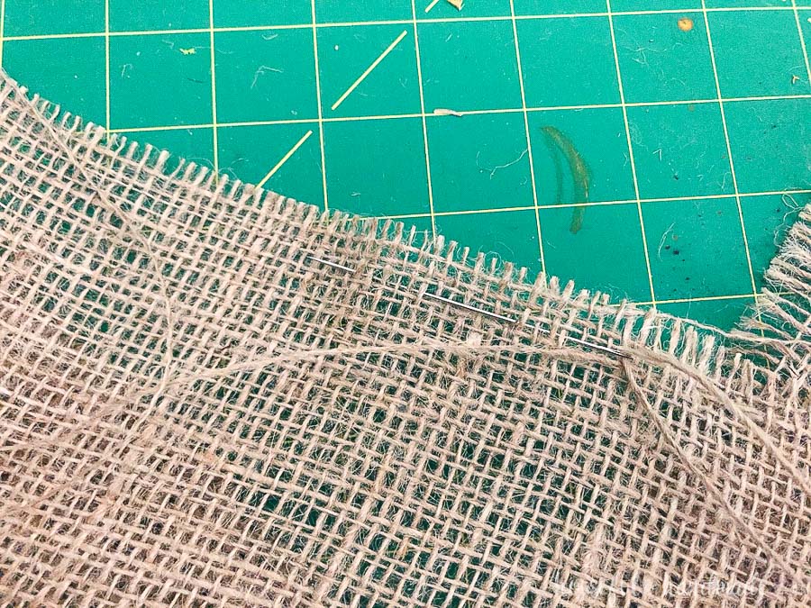 Needle making gathering stitch in the burlap. 