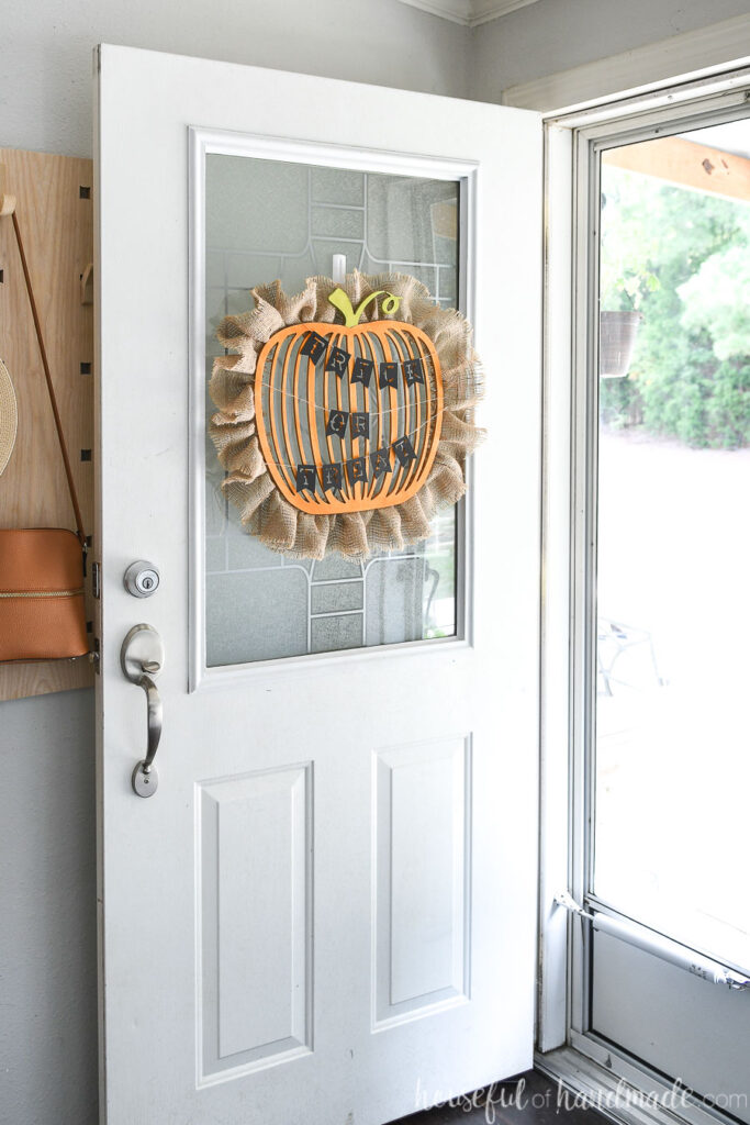 Entryway with door open showing the pumpkin wreath hanging on it with the Trick or Treat banner.