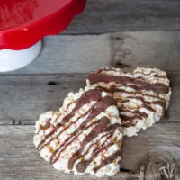 Two marshmallow popcorn treats shaped like hearts and drizzled with chocolate.