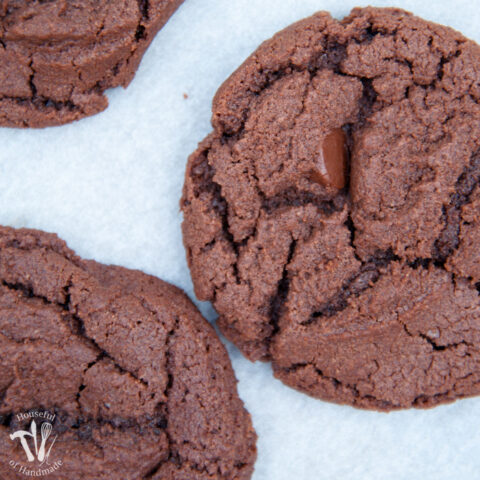 Close up of the double chocolate nutella cookies on a cookie sheet with a piece of parchment.