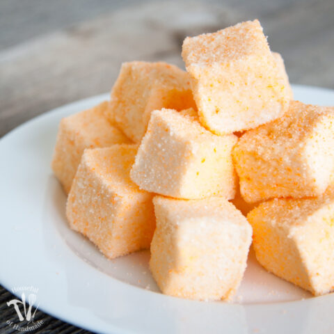 Stack of homemade orange marshmallow peeps covered in orange colored sugar on a plate.