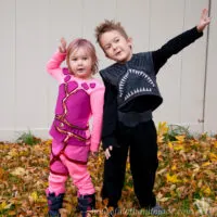 Young boy dressed in a DIY Sharkboy costume and little girl in a DIY lava girl costume outside in a pile of leaves.