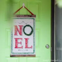 DIY Christmas scroll with Noel on it hanging on a front door as a wreath.