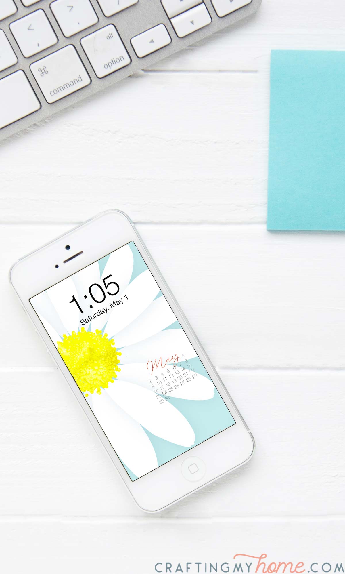 Free digital background for May on the screen of a white iPhone on a desk next to a keyboard and blue post-it notes. 