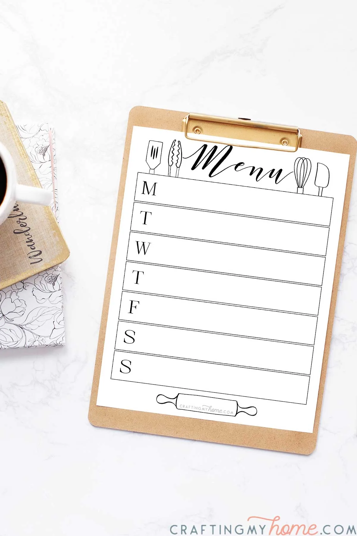 White printable menu board with utensil designs on it clipped to a clipboard next to a planner and cup of coffee. 