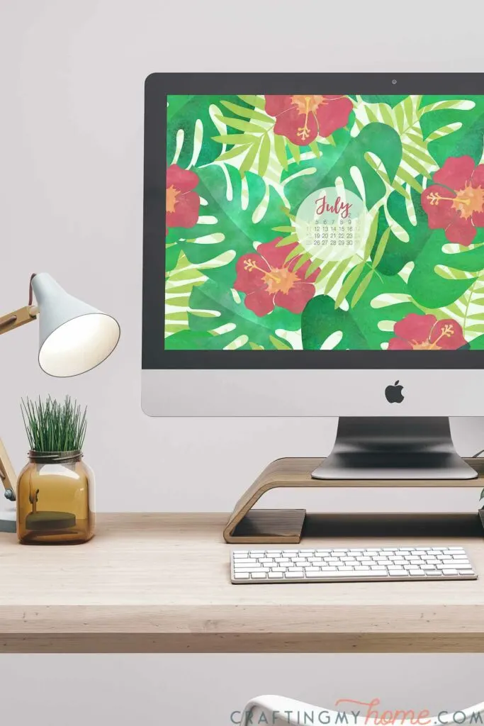Desktop computer with free digital wallpaper for July on the screen with a July 2021 calendar. 