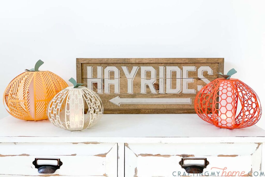 Fall vignette with DIY pumpkin lanterns made from paper and a neutral wood hayride sign on a farmhouse console table. 