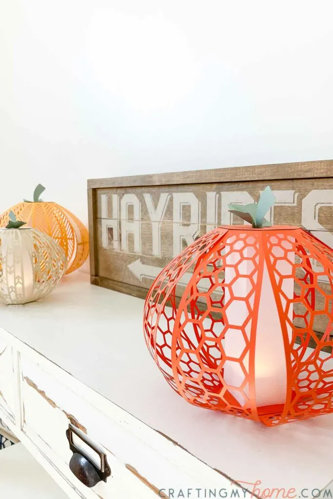 Angled view of the DIY pumpkin lanterns on a table with a wood sign in the background. 