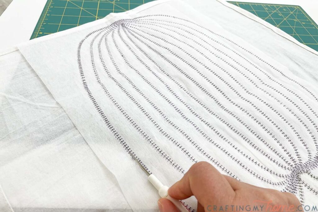 Using a seam ripper to remove the tear away stabilizer from the back of the tea towels. 