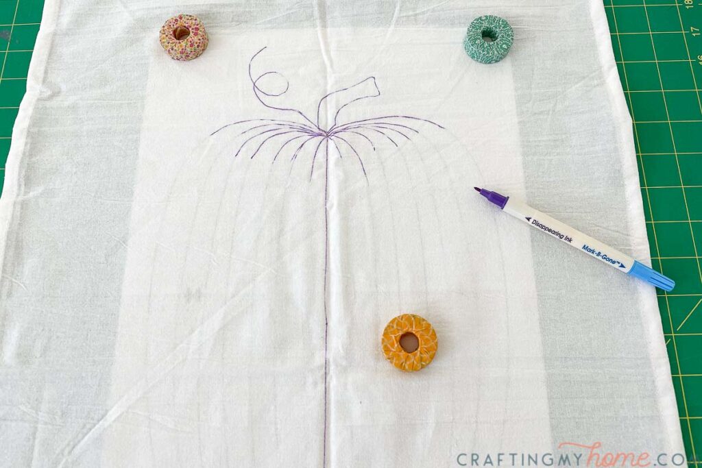 Tea towel laying over the pattern being traced with a fabric marker. 