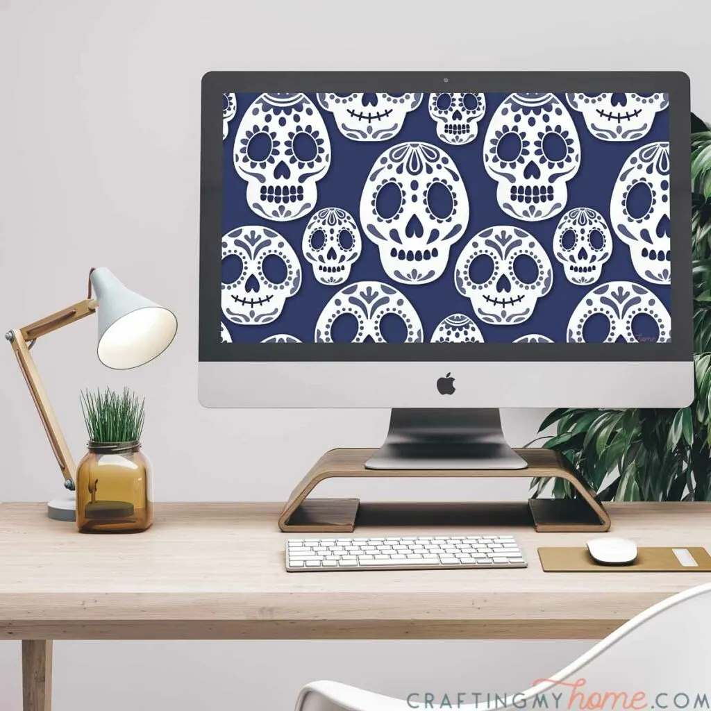 Computer sitting on a desk with the October digital background of sugar skulls on it. 