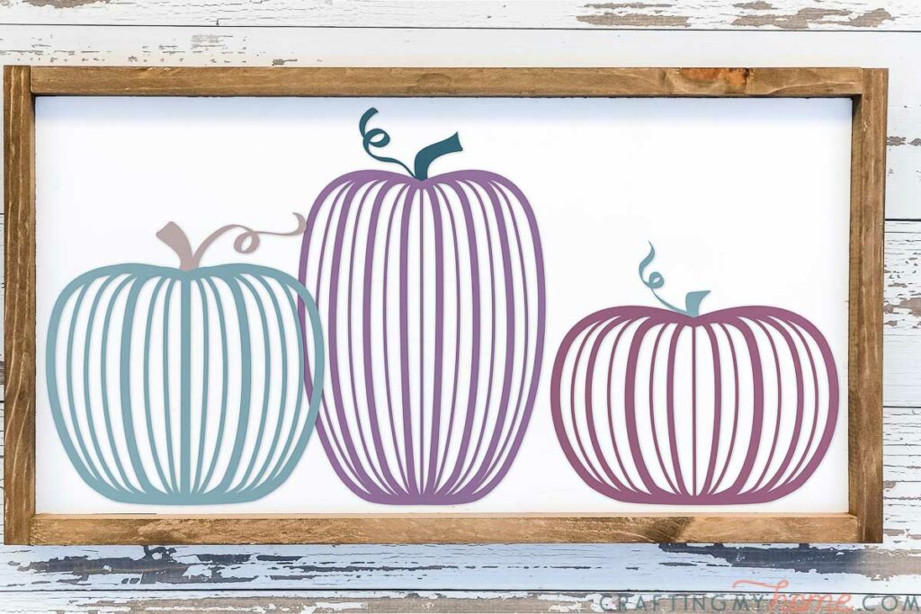Three modern line pumpkin SVG files cut out of vinyl on a white sign with wood frame. 
