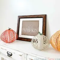Pumpkin patch printable art in a frame next to paper pumpkin lanterns.