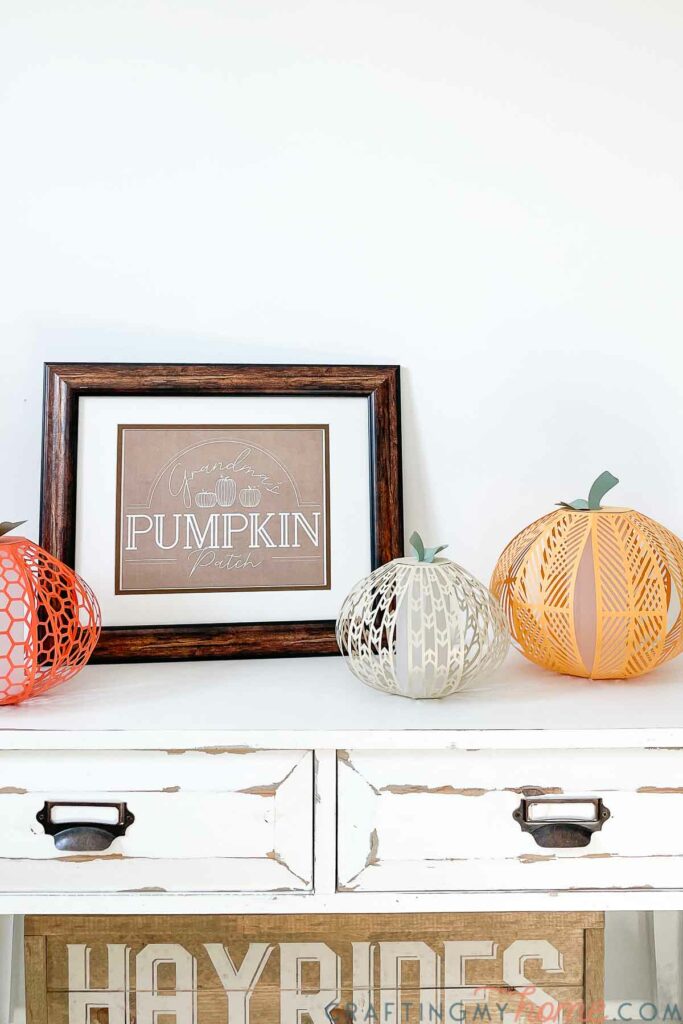 Fall vignette with Grandma's Pumpkin Patch fall sign and decorative pumpkins on a white console table above a Hayrides wood sign. 