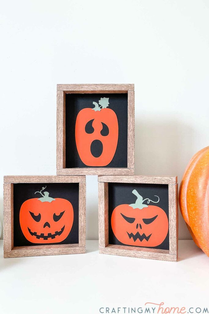 Three simple Halloween signs with 3 different jack-o-lanterns on them stacked in a triangle. 
