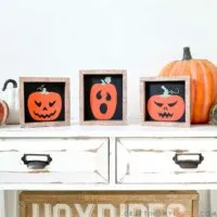 Three simple Halloween signs of jack-o-lanters on a black background with faux wood frames.