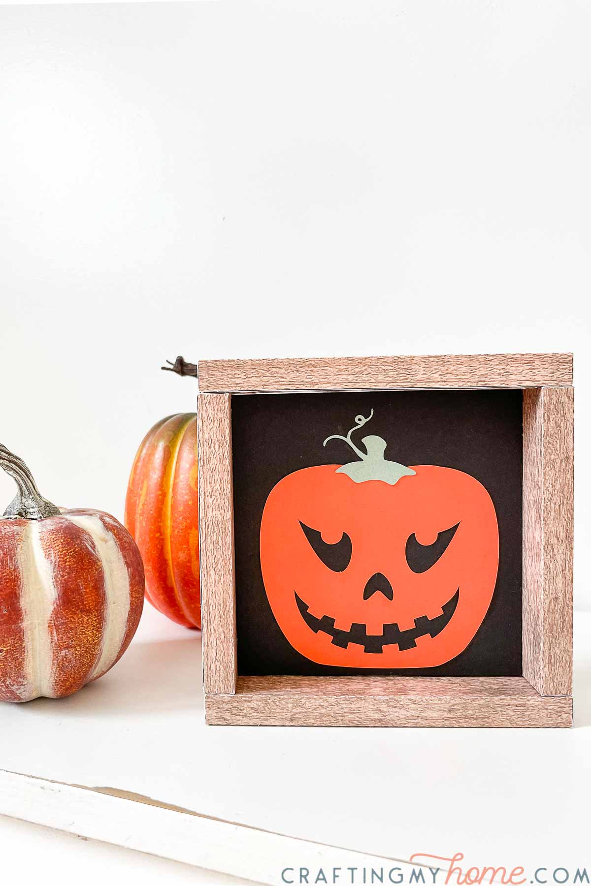 Orange paper jack-o-lantern in a square faux-wood paper frame