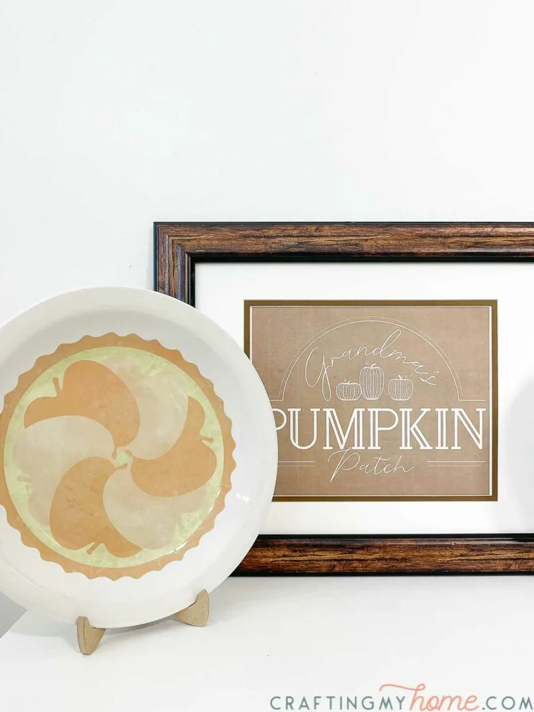 DIY decorative plate craft with apple pie design in front of a pumpkin patch sign. 