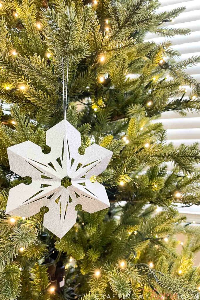 3D paper snowflake decoration hanging on a Christmas tree. 