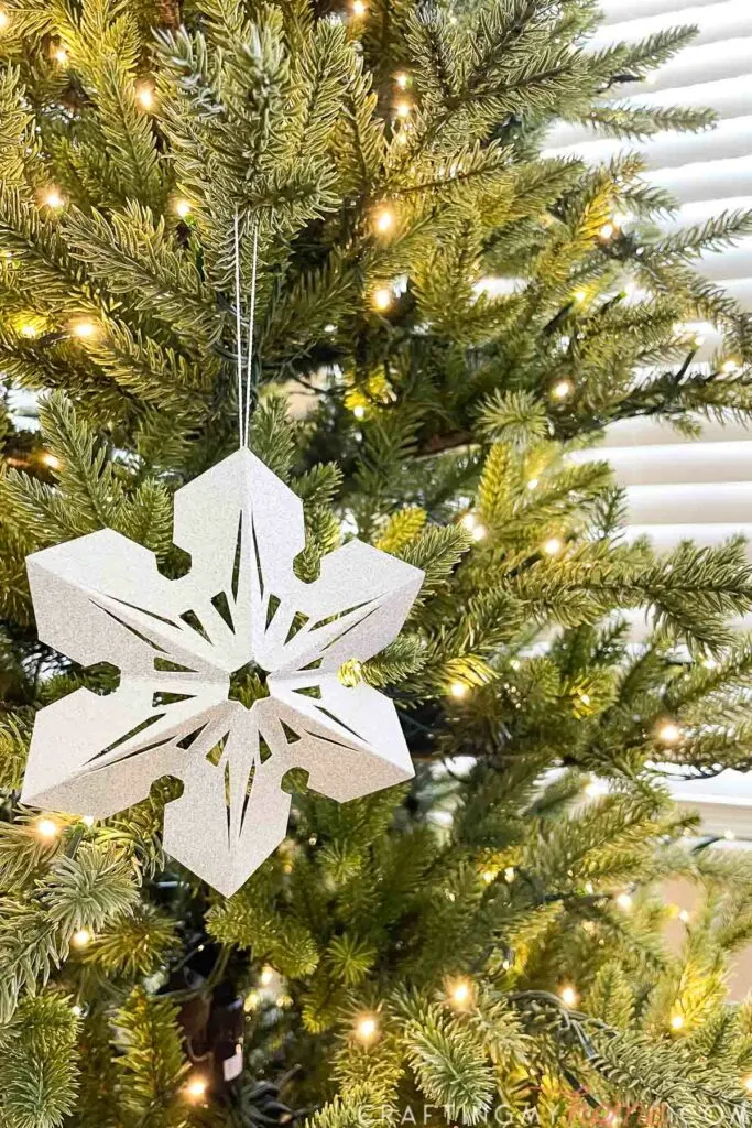3D paper snowflake decoration hanging on a Christmas tree. 