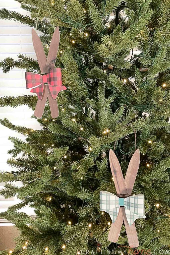Two ski Christmas ornaments hanging on a Christmas tree. 