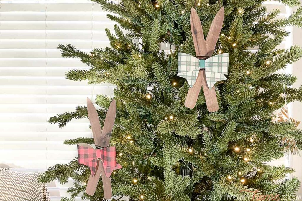 Two wooden ski ornaments hanging on a Christmas tree.