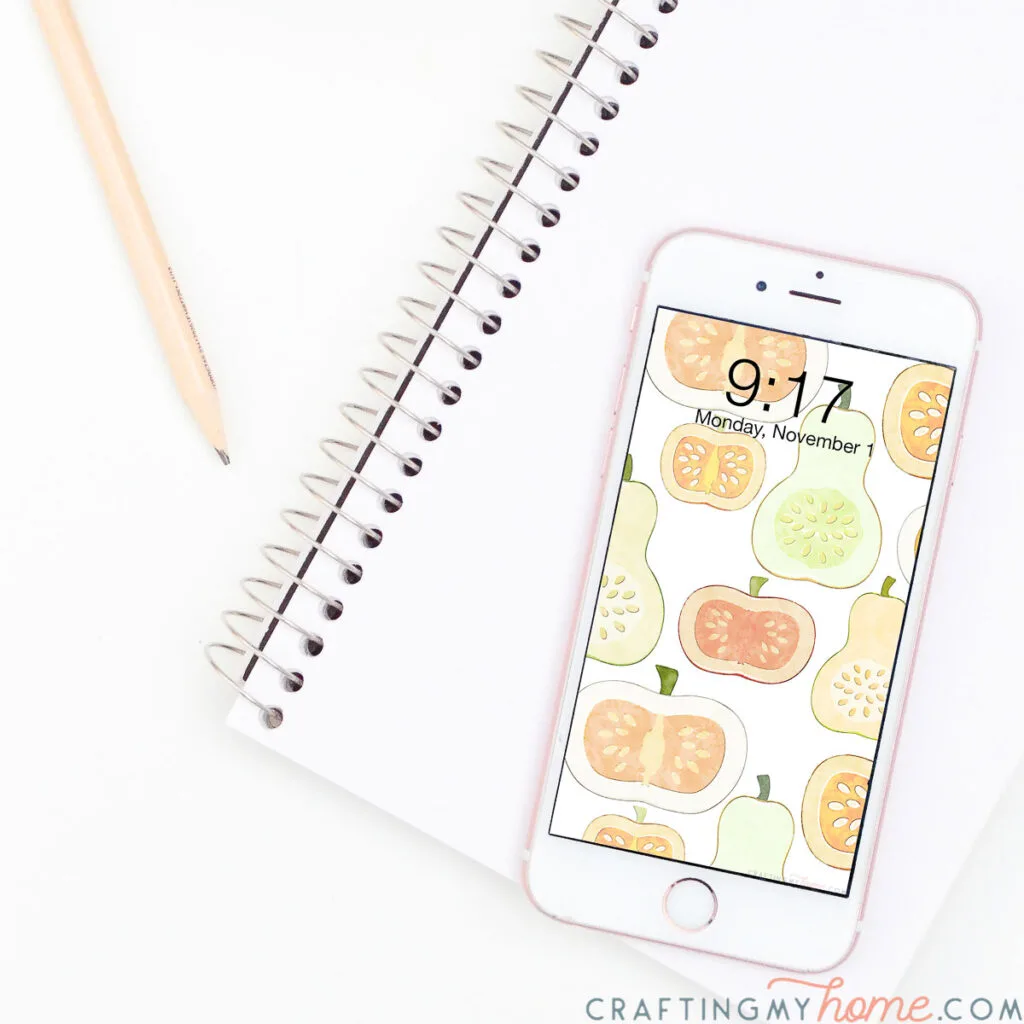 White iPhone with watercolor digital background of pumpkins and gourds on the lock screen. 