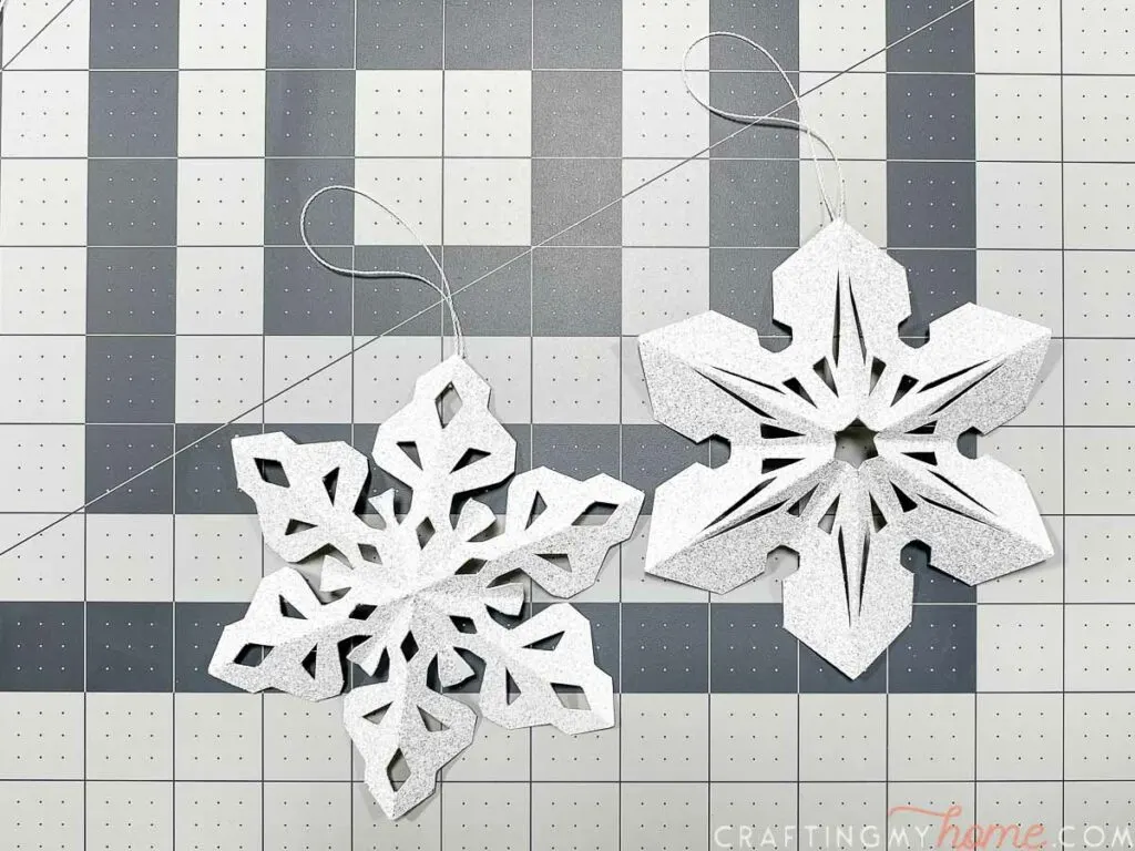 Completed paper 3D snowflake ornaments sitting on a cutting mat. 