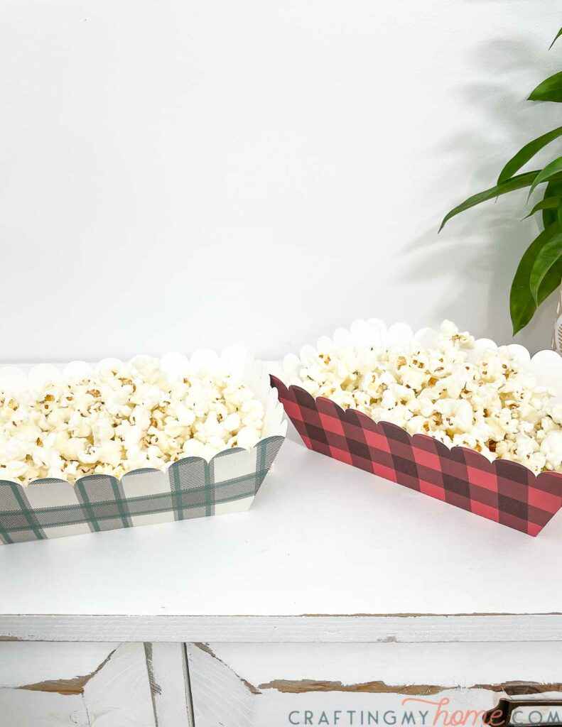 Two big rectangle paper food boats with popcorn in them. 