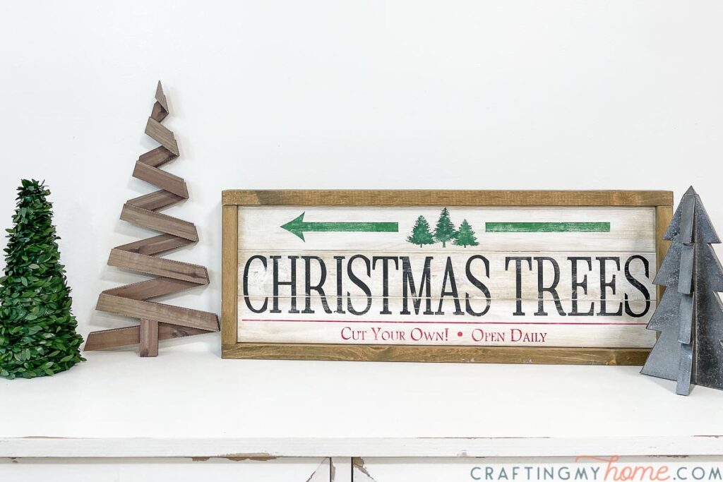 Christmas vignette with wood Christmas tree farm sign, faux wood Christmas tree and two other Christmas trees. 