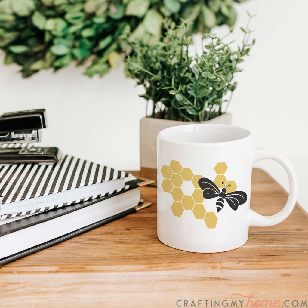 Bumble bee SVG with honeycomb on a white coffee mug sitting on a desk.