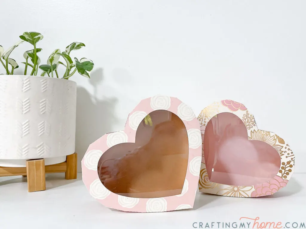 Heart chocolate boxes with clear windows in the lids sitting on their sides. 