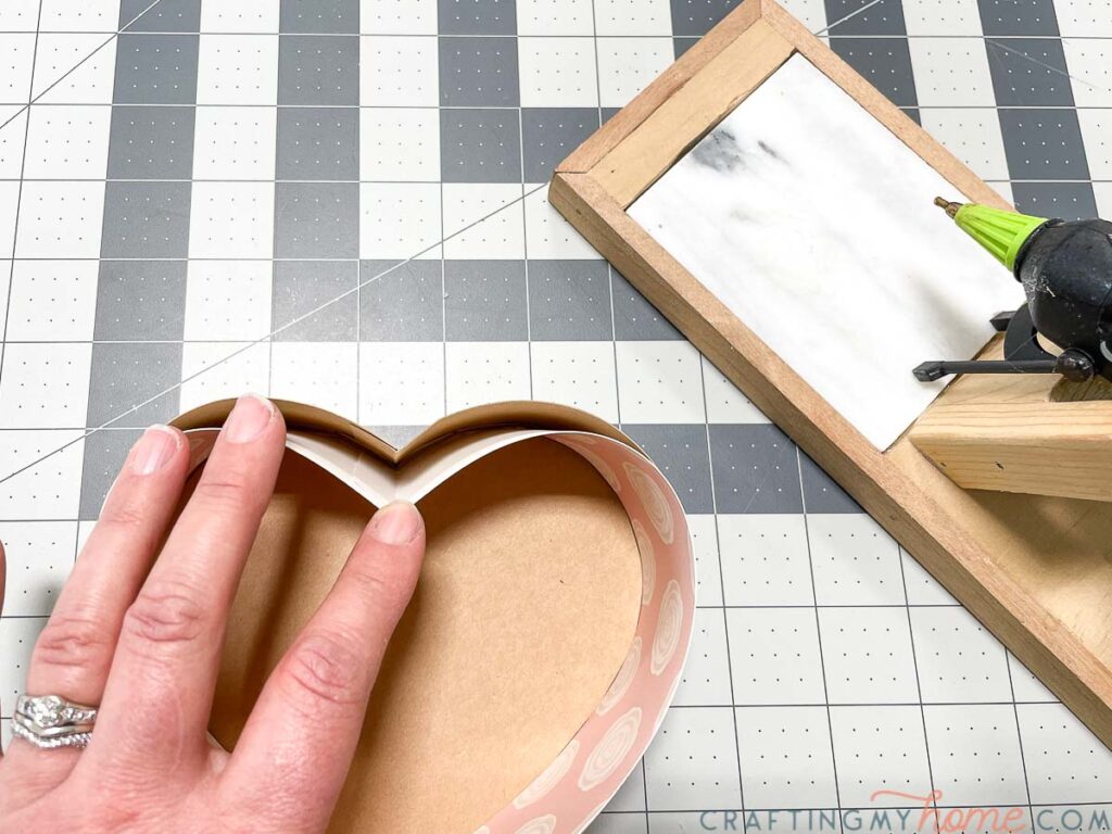 Securing the inside reinforcement pieces of the heart chocolate box with hot glue. 