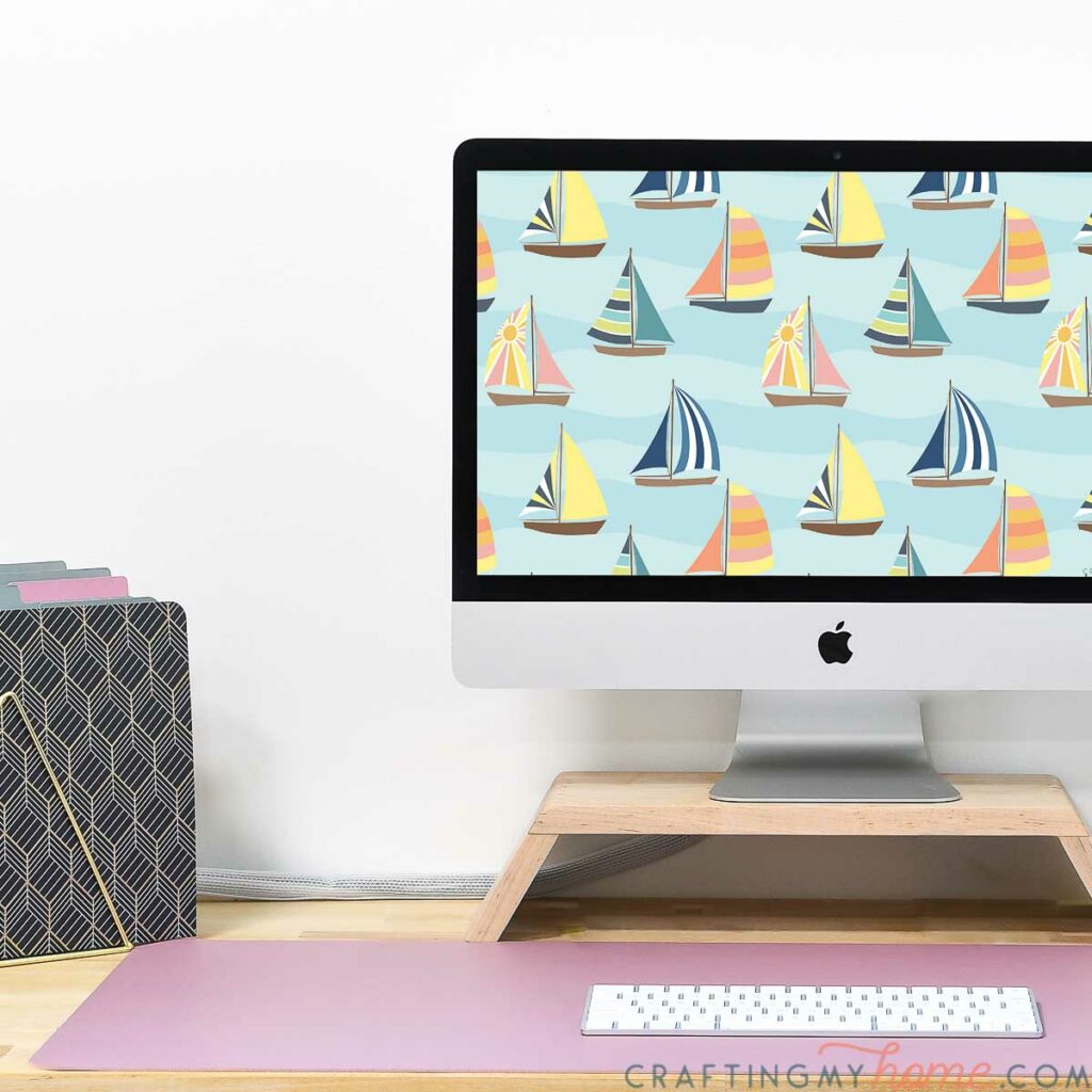 iMac computer on a desk with the sailboat themed digital background on the screen. 