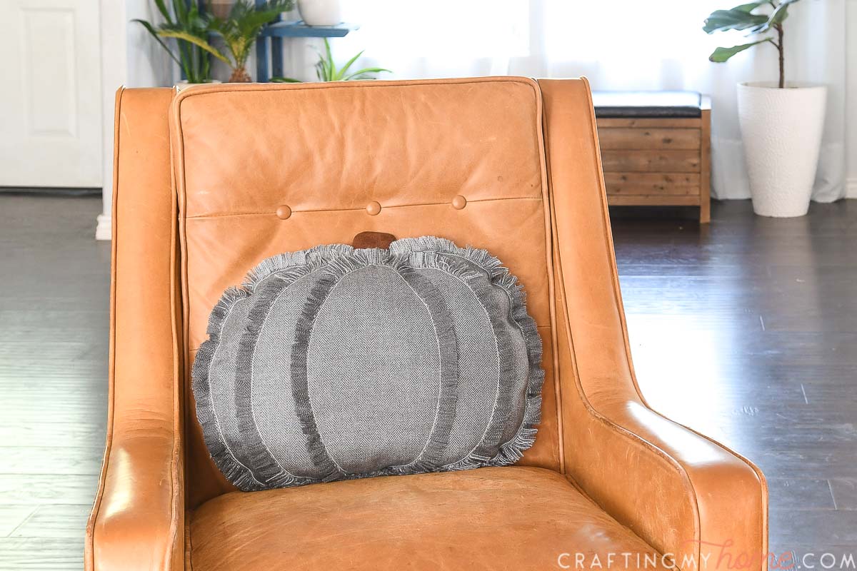 Frayed edge modern pumpkin throw pillow on a chair. 