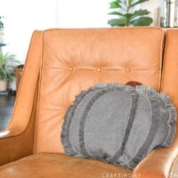DIY pumpkin pillow made from modern fabric on a chair.