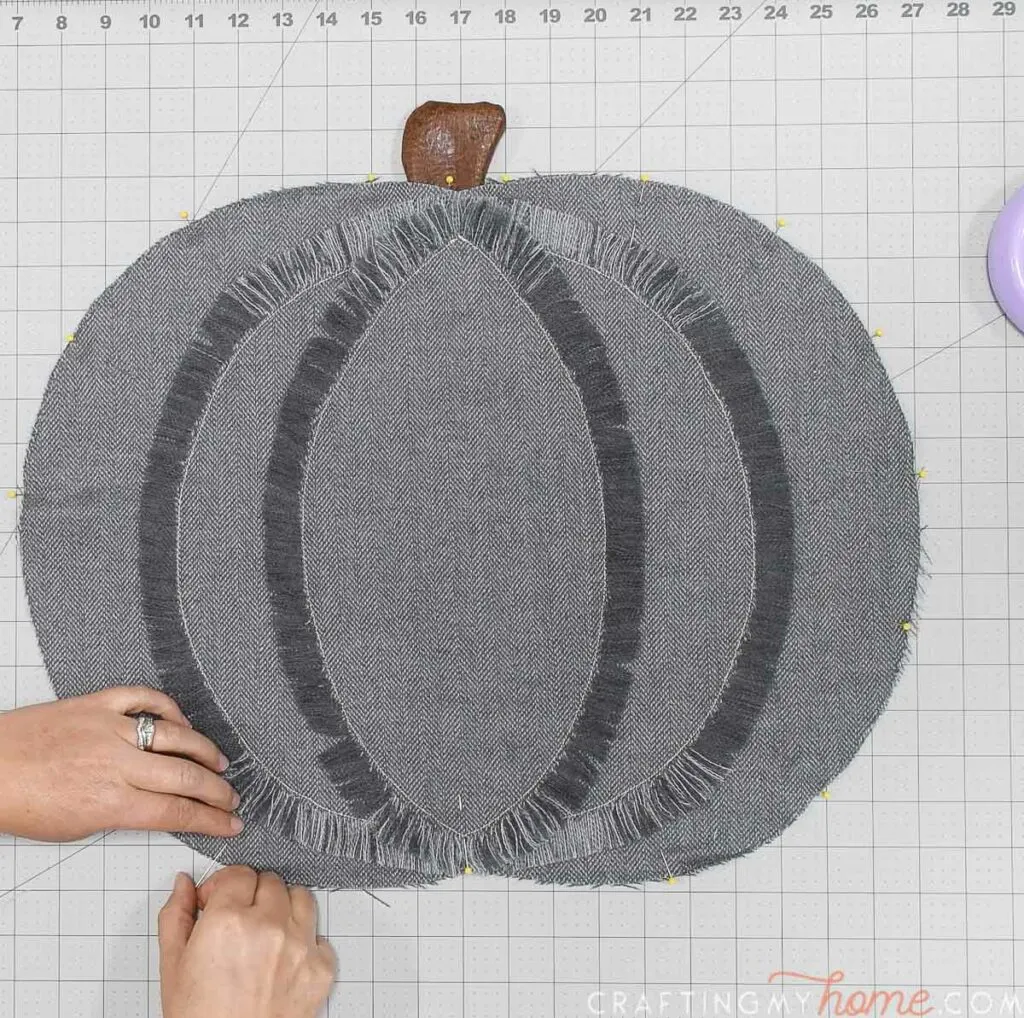 Pinning the top piece of the pumpkin pillow onto the back with right sides facing out. 