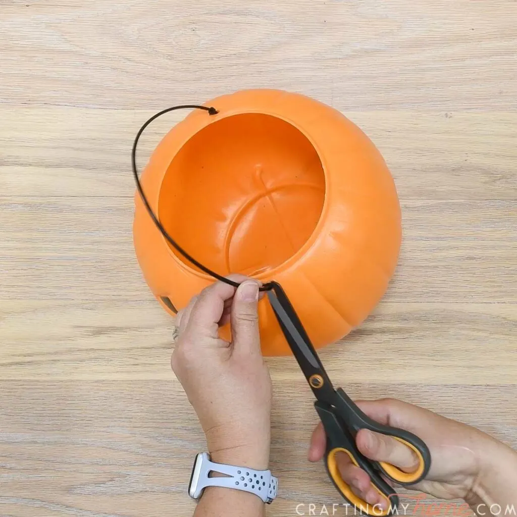 Cutting the handle off a pumpkin trick or treat pail. 