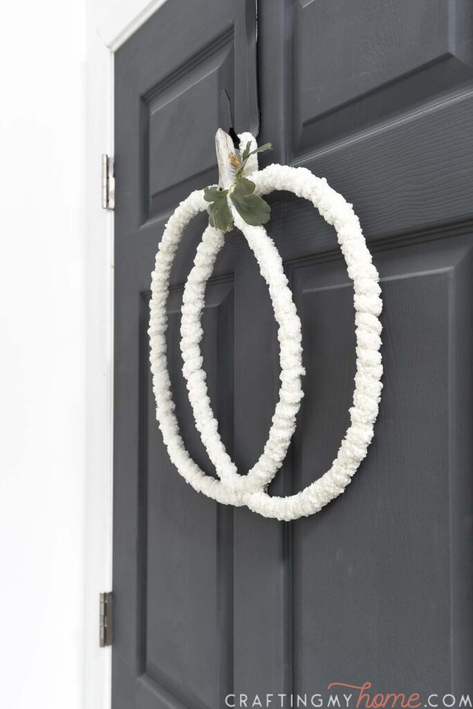 Side view of the yarn covered pumpkin wreath on a door. 