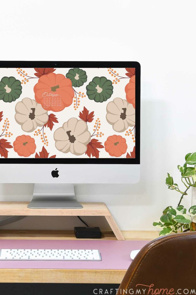 Pumpkin and fall leaves digital wallpaper on the screen of a desktop computer. 